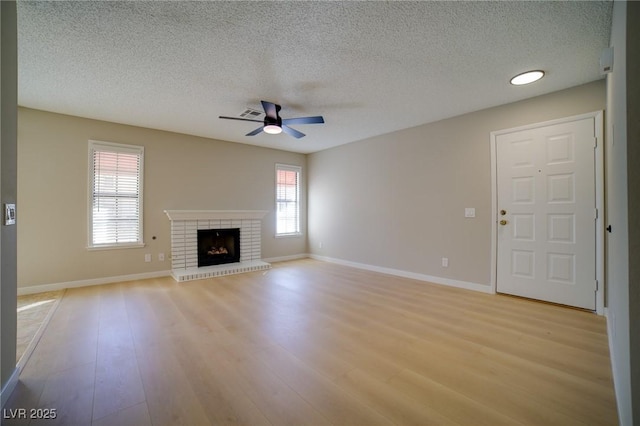 6649 W Tropicana Ave Unit 101, Las Vegas, NV 89103 - unfurnished living room featuring ceiling fan, light wood-type flooring, a textured ceiling, a fireplace, and baseboards