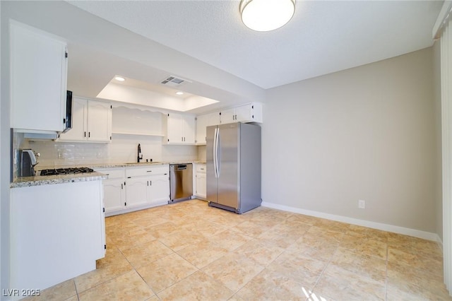6649 W Tropicana Ave Unit 101, Las Vegas, NV 89103 - kitchen with appliances with stainless steel finishes, a sink, a tray ceiling, open shelves, and white cabinets