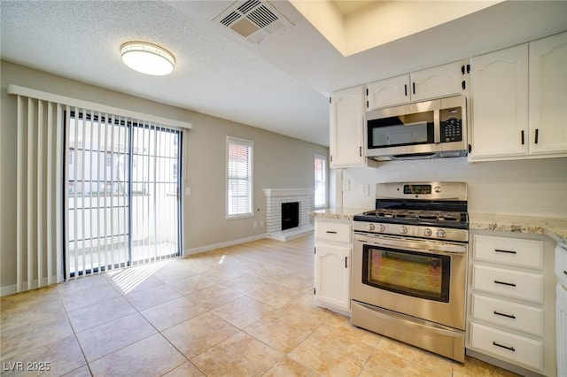 6649 W Tropicana Ave Unit 101, Las Vegas, NV 89103 - kitchen with stainless steel appliances, white cabinetry, light stone countertops, and baseboards