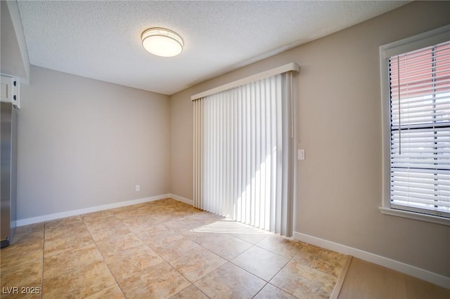 6649 W Tropicana Ave Unit 101, Las Vegas, NV 89103 - tiled empty room with a textured ceiling and baseboards