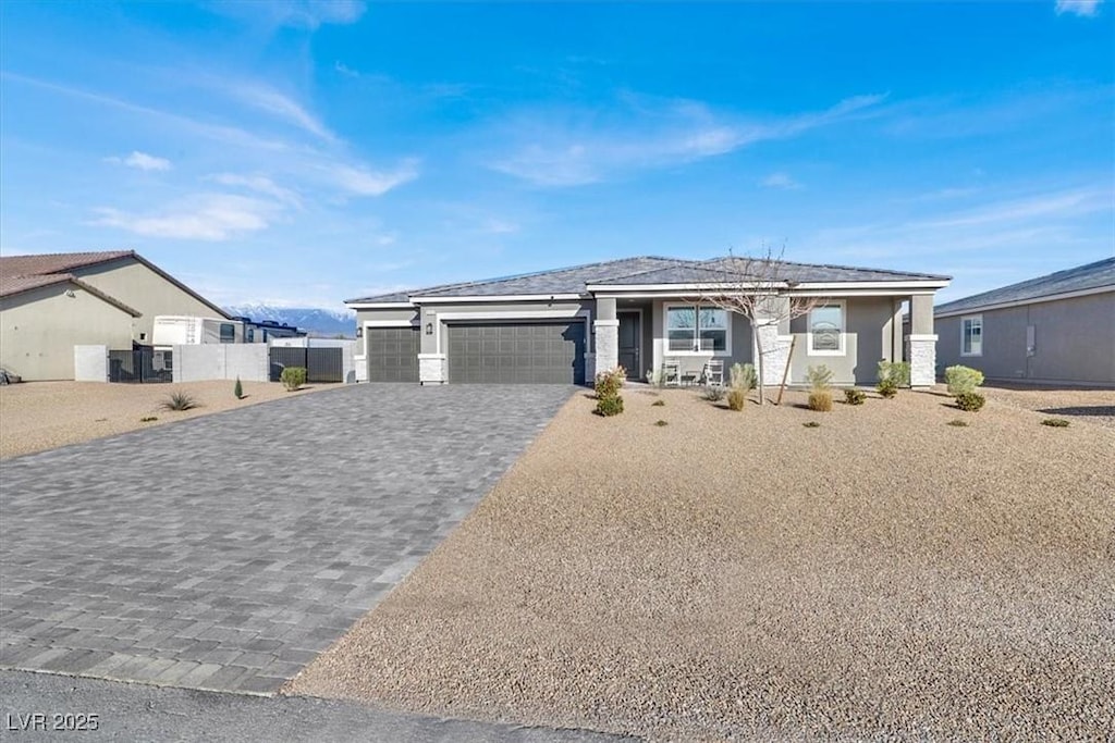 prairie-style house featuring decorative driveway, fence, and an attached garage