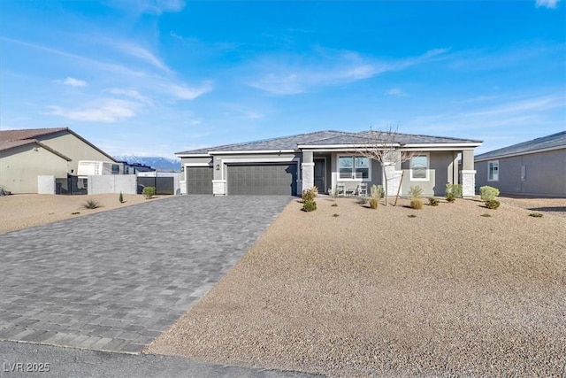 prairie-style house featuring decorative driveway, fence, and an attached garage