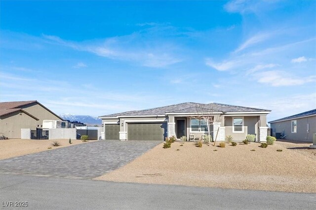 view of front of home with stucco siding, an attached garage, decorative driveway, and fence