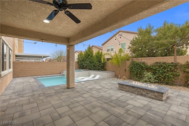 view of patio with a fenced backyard, a fire pit, and an in ground hot tub