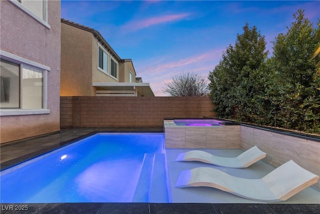 pool at dusk featuring an in ground hot tub, a fenced in pool, and a fenced backyard