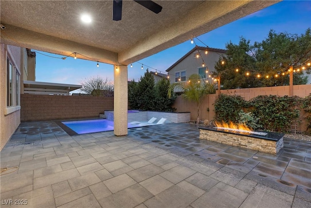 view of patio with a fenced in pool, a fenced backyard, ceiling fan, and a fire pit