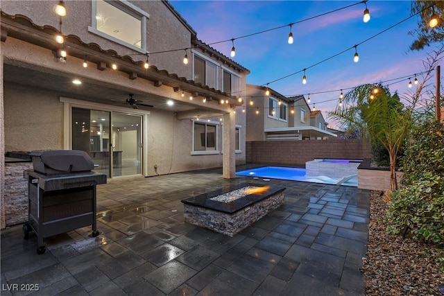 patio terrace at dusk featuring a ceiling fan, a fire pit, and a fenced backyard
