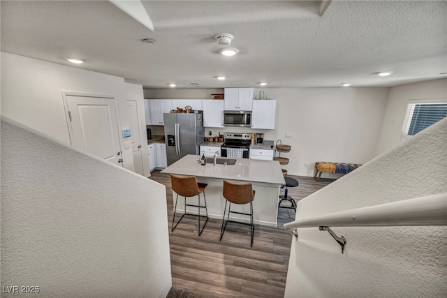 3725 Celesta Vista Ave, Henderson, NV 89044 - kitchen with appliances with stainless steel finishes, white cabinets, a breakfast bar, dark wood-style floors, and a sink