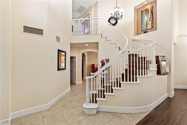 9517 Spanish Steps Ln, Las Vegas, NV 89117 - stairs with baseboards, a high ceiling, arched walkways, a chandelier, and tile patterned flooring