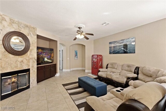 9517 Spanish Steps Ln, Las Vegas, NV 89117 - living area featuring arched walkways, light tile patterned flooring, a ceiling fan, a fireplace, and baseboards