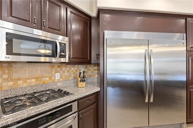 9517 Spanish Steps Ln, Las Vegas, NV 89117 - kitchen with stainless steel appliances, dark brown cabinetry, tasteful backsplash, and light stone countertops