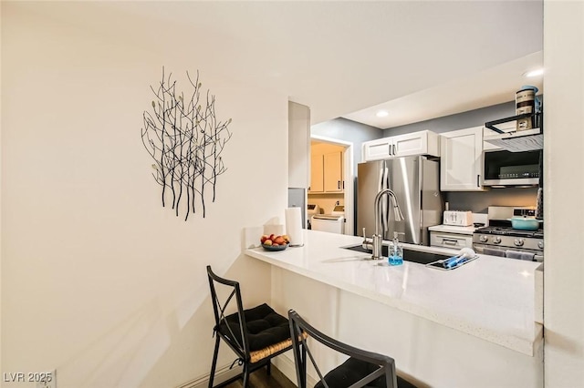 950 Seven Hills Dr Unit 814, Henderson, NV 89052 - kitchen with white cabinetry, independent washer and dryer, stainless steel appliances, a sink, and a peninsula