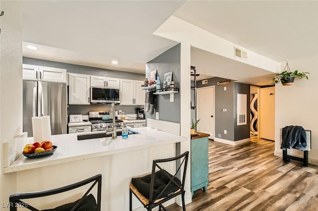 950 Seven Hills Dr Unit 814, Henderson, NV 89052 - kitchen featuring a sink, a kitchen breakfast bar, appliances with stainless steel finishes, light wood-style flooring, and visible vents
