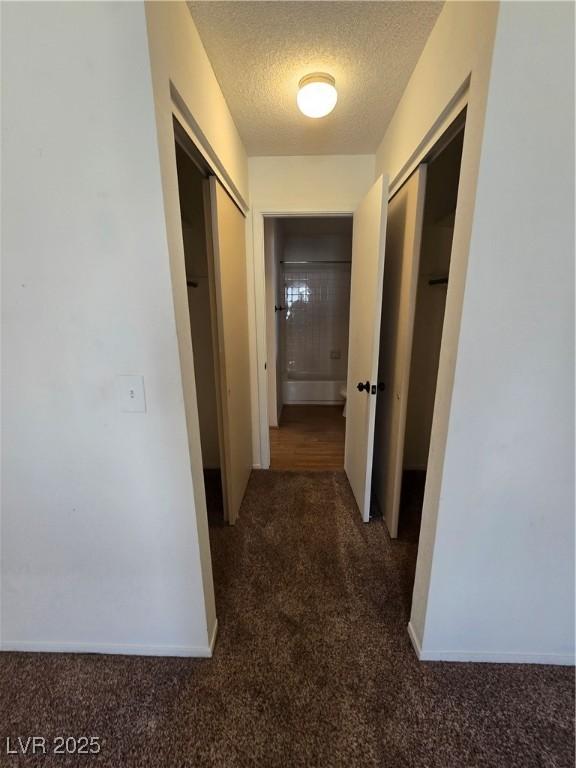 hall with carpet flooring and a textured ceiling