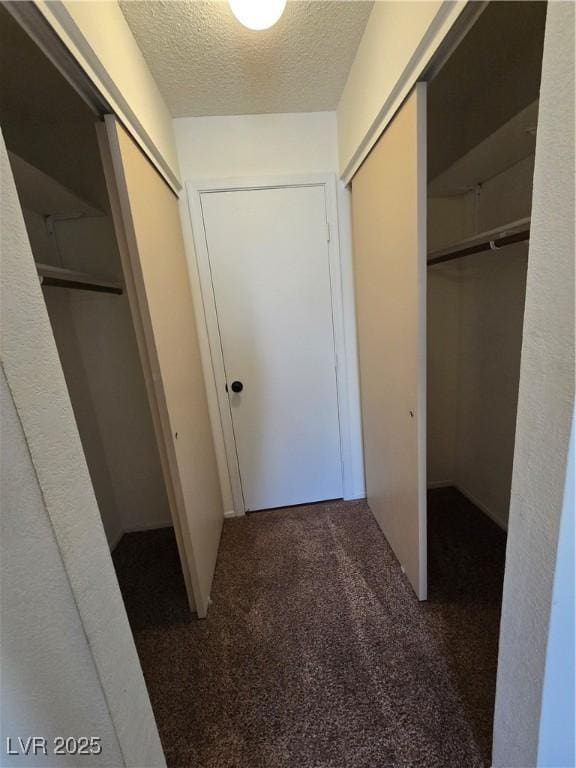corridor with a textured ceiling and carpet floors