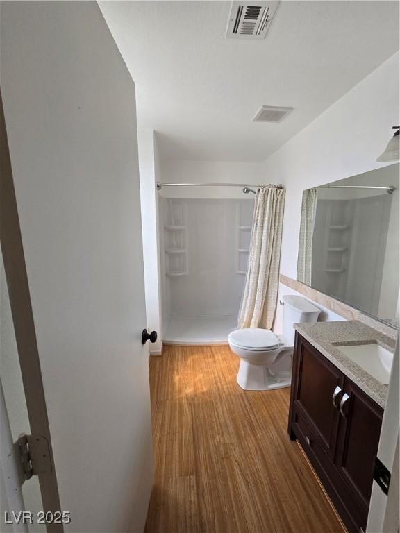 bathroom with vanity, a shower with curtain, toilet, visible vents, and wood finished floors