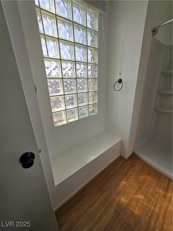 bathroom featuring wood finished floors, baseboards, and walk in shower