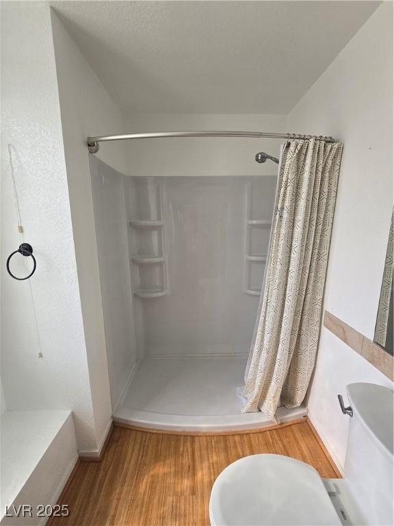 bathroom with wood finished floors, a shower with shower curtain, and baseboards