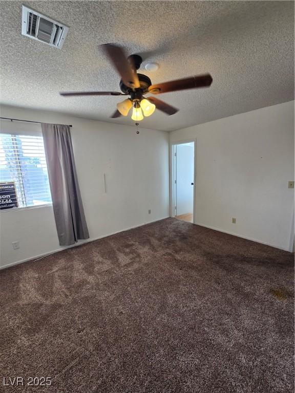 carpeted empty room featuring a textured ceiling, ceiling fan, and visible vents