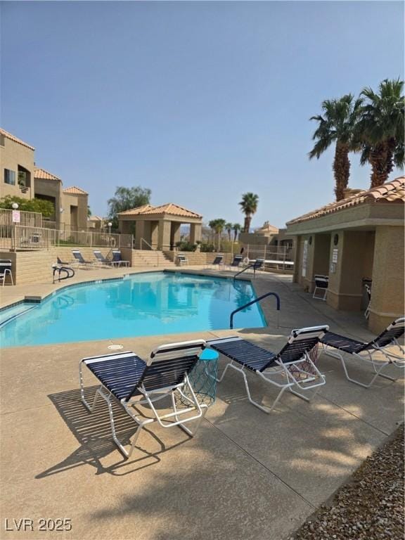pool with a patio area and fence