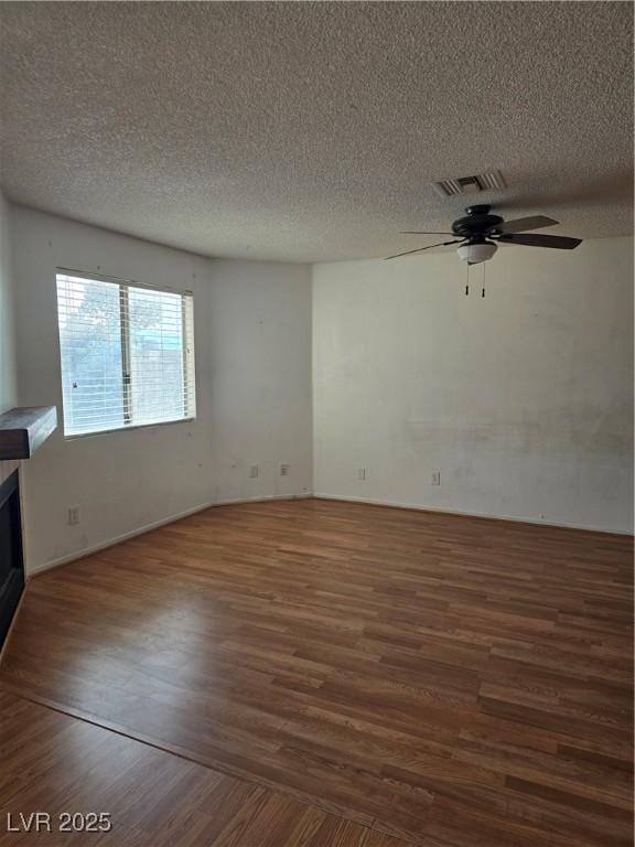 unfurnished living room featuring a textured ceiling, wood finished floors, ceiling fan, and visible vents