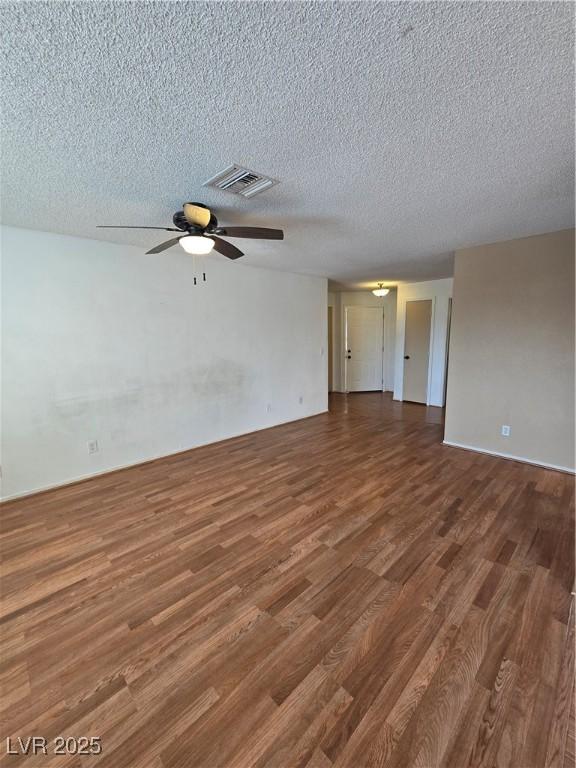 spare room featuring visible vents, ceiling fan, wood finished floors, and a textured ceiling