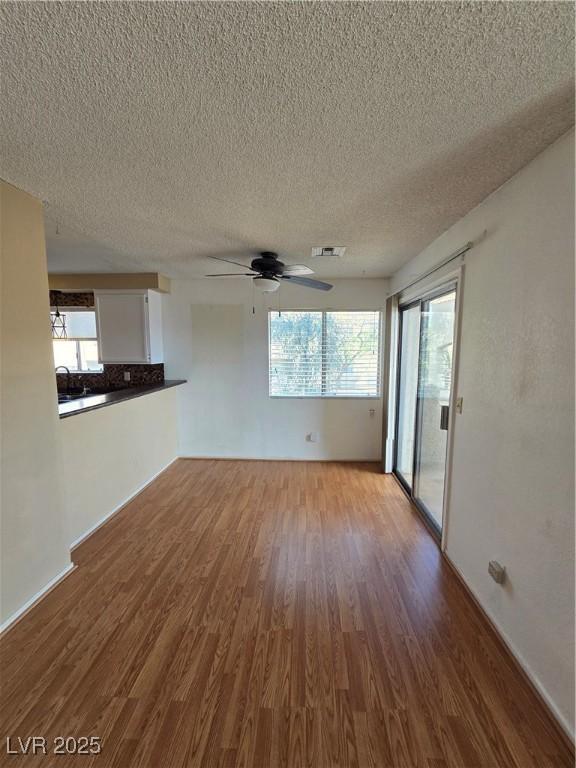 unfurnished room featuring visible vents, a ceiling fan, wood finished floors, and a textured ceiling