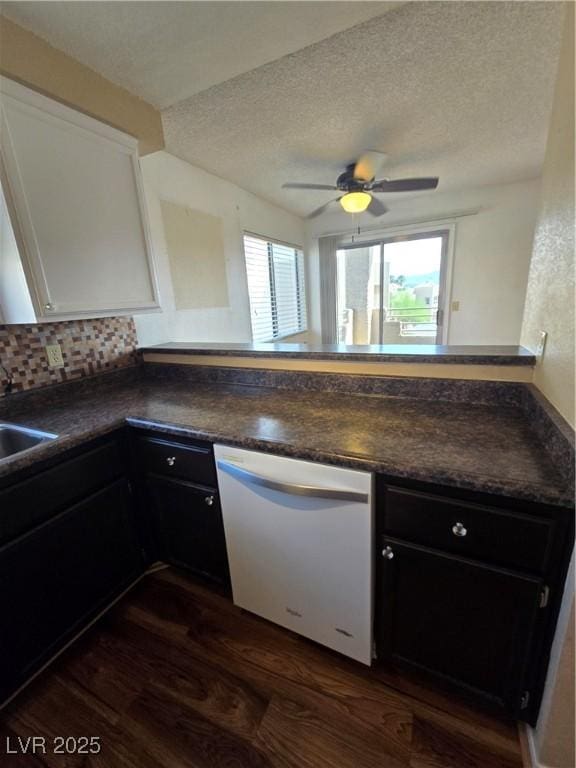 kitchen featuring dark wood-type flooring, dark countertops, and white dishwasher