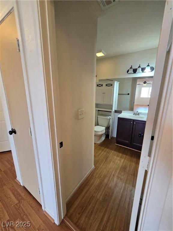 bathroom with toilet, wood finished floors, vanity, and visible vents