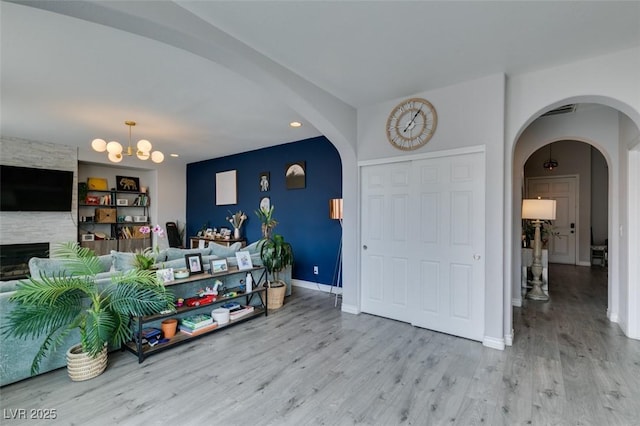 11769 Via Vera Cruz Ct, Las Vegas, NV 89138 - entrance foyer with arched walkways, wood finished floors, a chandelier, a large fireplace, and baseboards