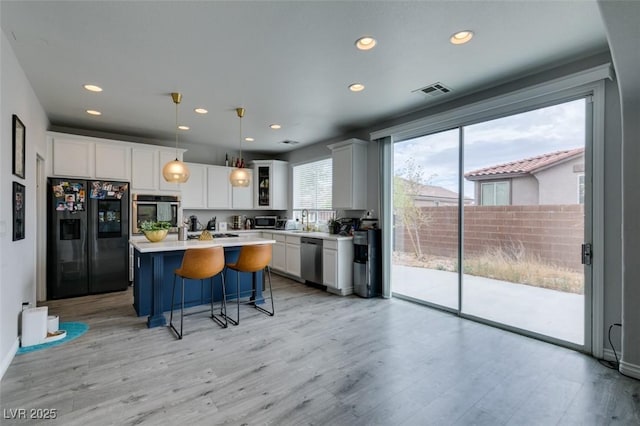 11769 Via Vera Cruz Ct, Las Vegas, NV 89138 - kitchen featuring stainless steel appliances, light countertops, a breakfast bar, a center island, and white cabinets