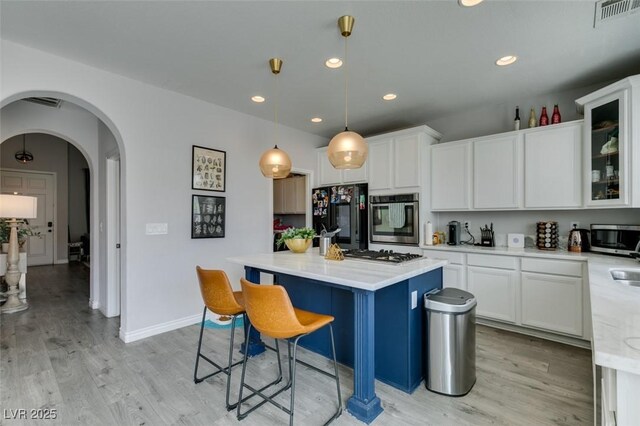 11769 Via Vera Cruz Ct, Las Vegas, NV 89138 - kitchen with stainless steel appliances, light wood-style floors, a kitchen bar, white cabinetry, and recessed lighting