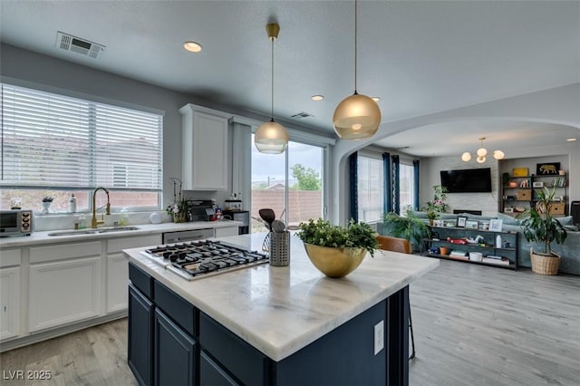 11769 Via Vera Cruz Ct, Las Vegas, NV 89138 - kitchen featuring a sink, arched walkways, stainless steel gas cooktop, light wood-type flooring, and light countertops