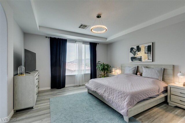 11769 Via Vera Cruz Ct, Las Vegas, NV 89138 - bedroom featuring a tray ceiling, baseboards, light wood-style flooring, and a chandelier
