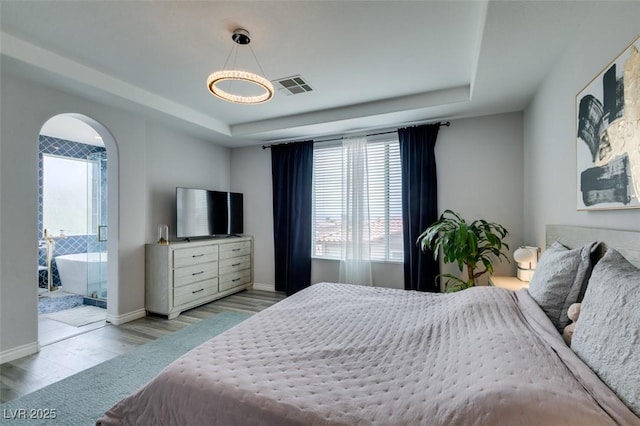 11769 Via Vera Cruz Ct, Las Vegas, NV 89138 - bedroom featuring multiple windows, a tray ceiling, wood finished floors, and arched walkways