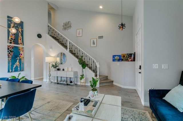 11769 Via Vera Cruz Ct, Las Vegas, NV 89138 - living area featuring high vaulted ceiling, arched walkways, stairway, wood finished floors, and baseboards