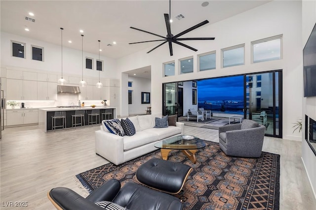 148 Tre Pietre St, Henderson, NV 89011 - living room with visible vents, ceiling fan, light wood-style floors, recessed lighting, and a towering ceiling
