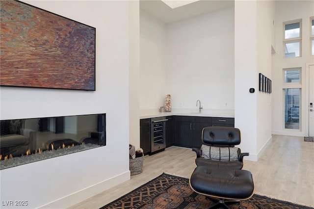 148 Tre Pietre St, Henderson, NV 89011 - sitting room featuring indoor wet bar, wine cooler, baseboards, and light wood-style flooring