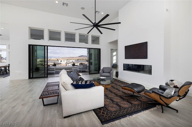 148 Tre Pietre St, Henderson, NV 89011 - living area featuring wood finished floors, a glass covered fireplace, visible vents, and recessed lighting