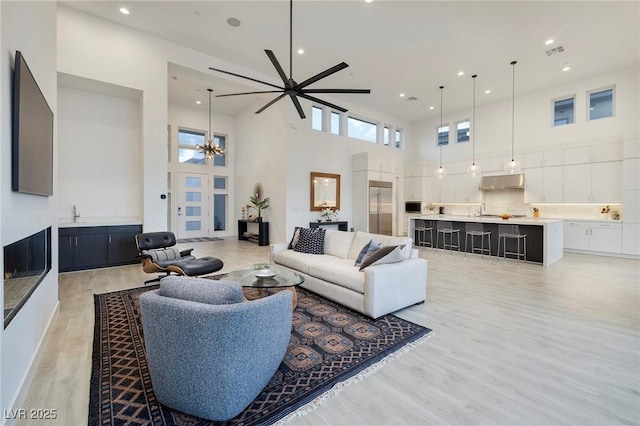 148 Tre Pietre St, Henderson, NV 89011 - living room with a towering ceiling, recessed lighting, light wood-style floors, visible vents, and ceiling fan with notable chandelier