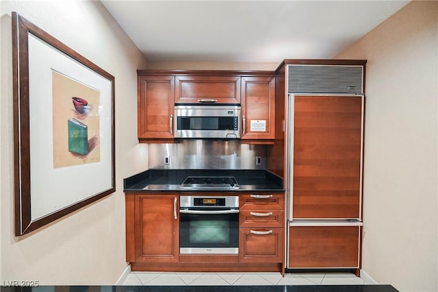 kitchen with dark countertops, baseboards, brown cabinets, and stainless steel appliances
