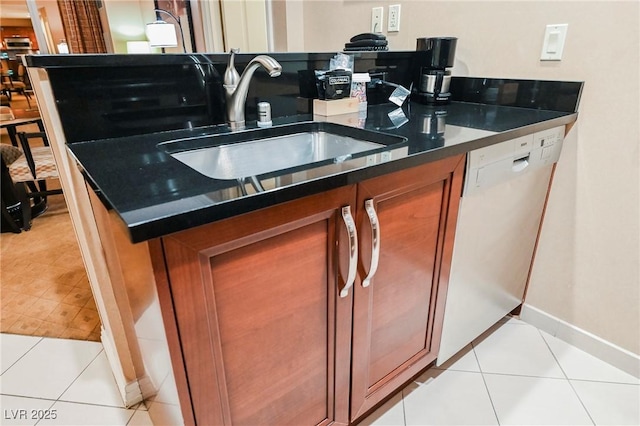 kitchen featuring brown cabinetry, baseboards, light tile patterned flooring, a sink, and dishwasher