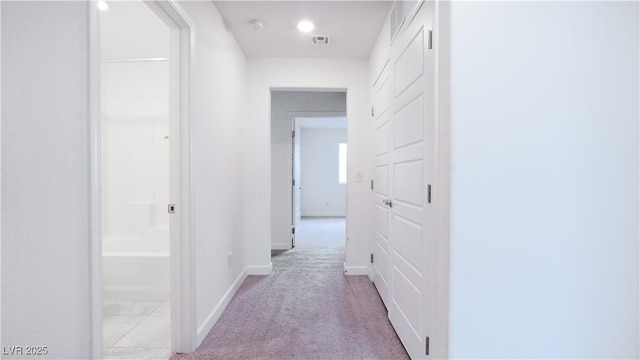 hall featuring light colored carpet, baseboards, and visible vents