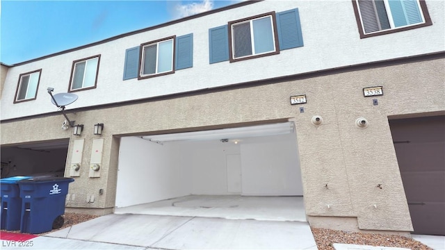 rear view of house featuring an attached garage and stucco siding