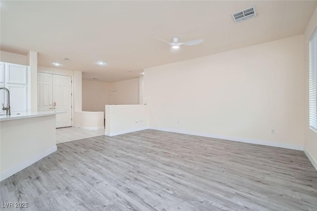 10580 Riva Grande Ct, Las Vegas, NV 89135 - unfurnished living room with light wood-style flooring, baseboards, recessed lighting, and a sink