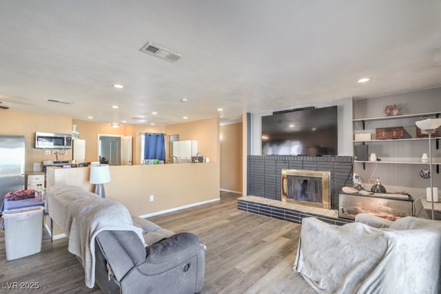 2450 Tournament St, Las Vegas, NV 89142 - living room featuring wood finished floors, visible vents, baseboards, recessed lighting, and a brick fireplace