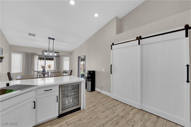 5988 Turtle River Ave, Las Vegas, NV 89156 - kitchen featuring visible vents, wine cooler, a barn door, light wood-style floors, and vaulted ceiling