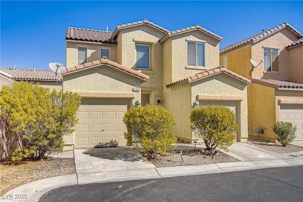 view of front of property featuring a tiled roof, concrete driveway, and stucco siding