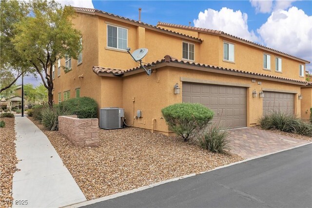 2376 Via Firenze, Henderson, NV 89044 - view of front of property with central air condition unit, an attached garage, stucco siding, a tile roof, and driveway