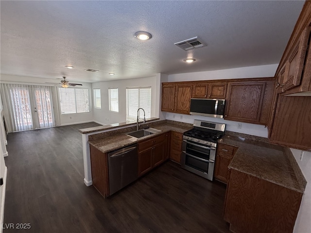 5661 Bonds Flat St, Las Vegas, NV 89148 - kitchen featuring stainless steel appliances, a sink, a textured ceiling, dark wood-style floors, and a peninsula